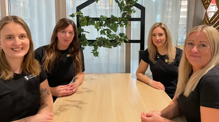 En grupp kvinnor som sitter runt ett träbord.