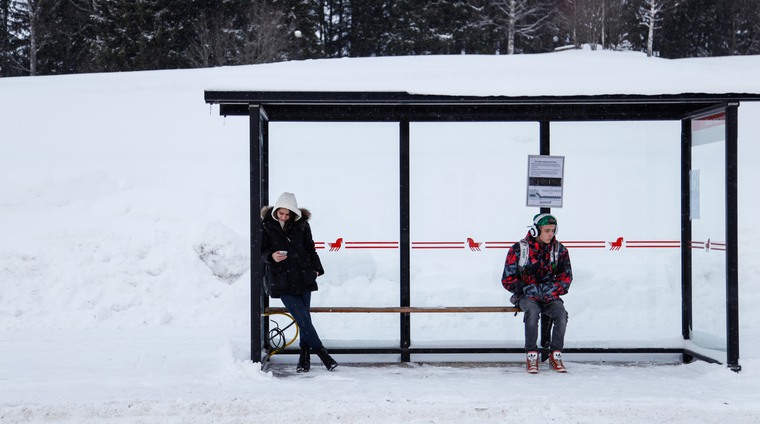 Två personer väntar vid en busshållplats
