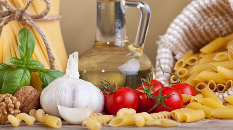Bilden visar lite olika ingredigenser som används vid matlagning.Vitlök, tomater, pasta och färska kryddor. 